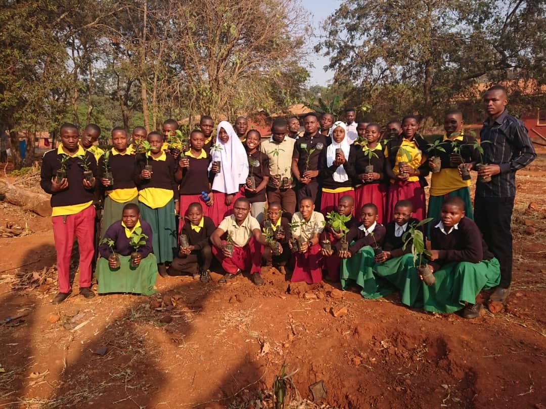 Students and educators posing together with seedlings after an outdoor activity.