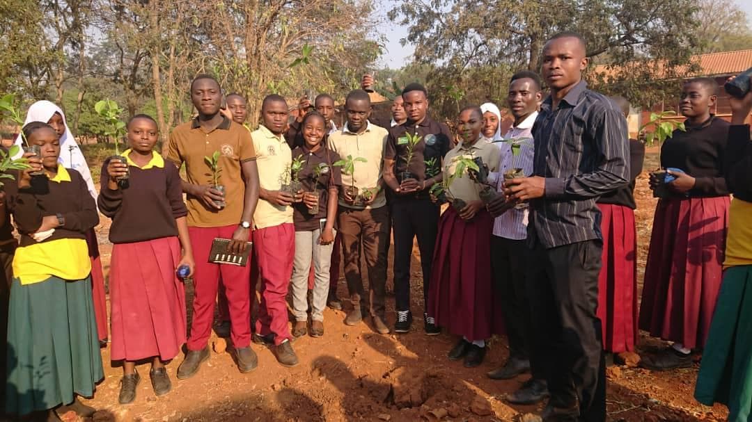 An environmental educator and students standing together with seedlings.