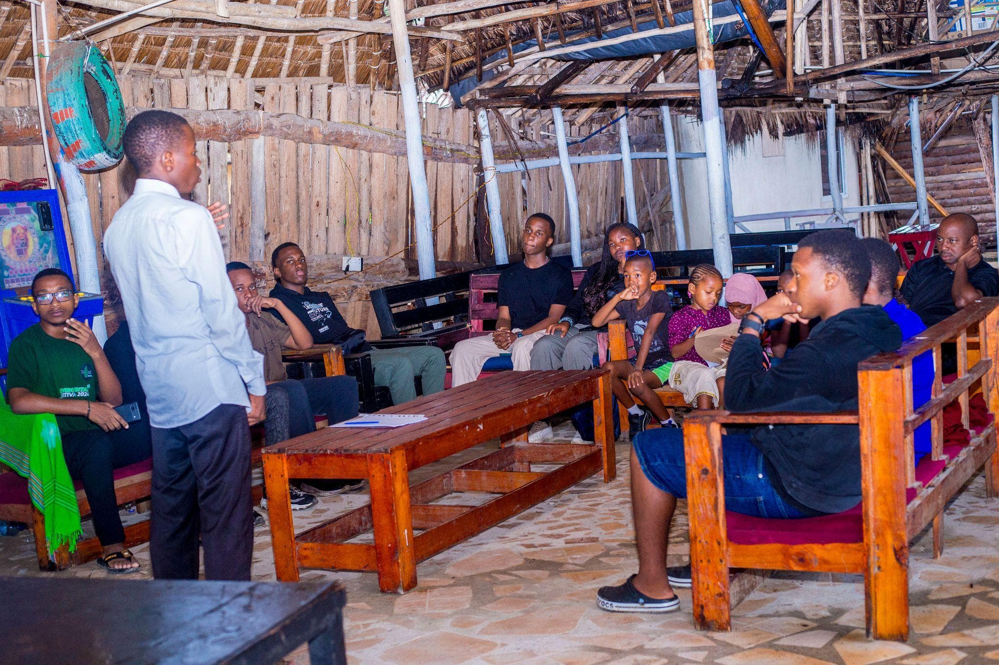 Participants listening to a speaker in a covered meeting space.