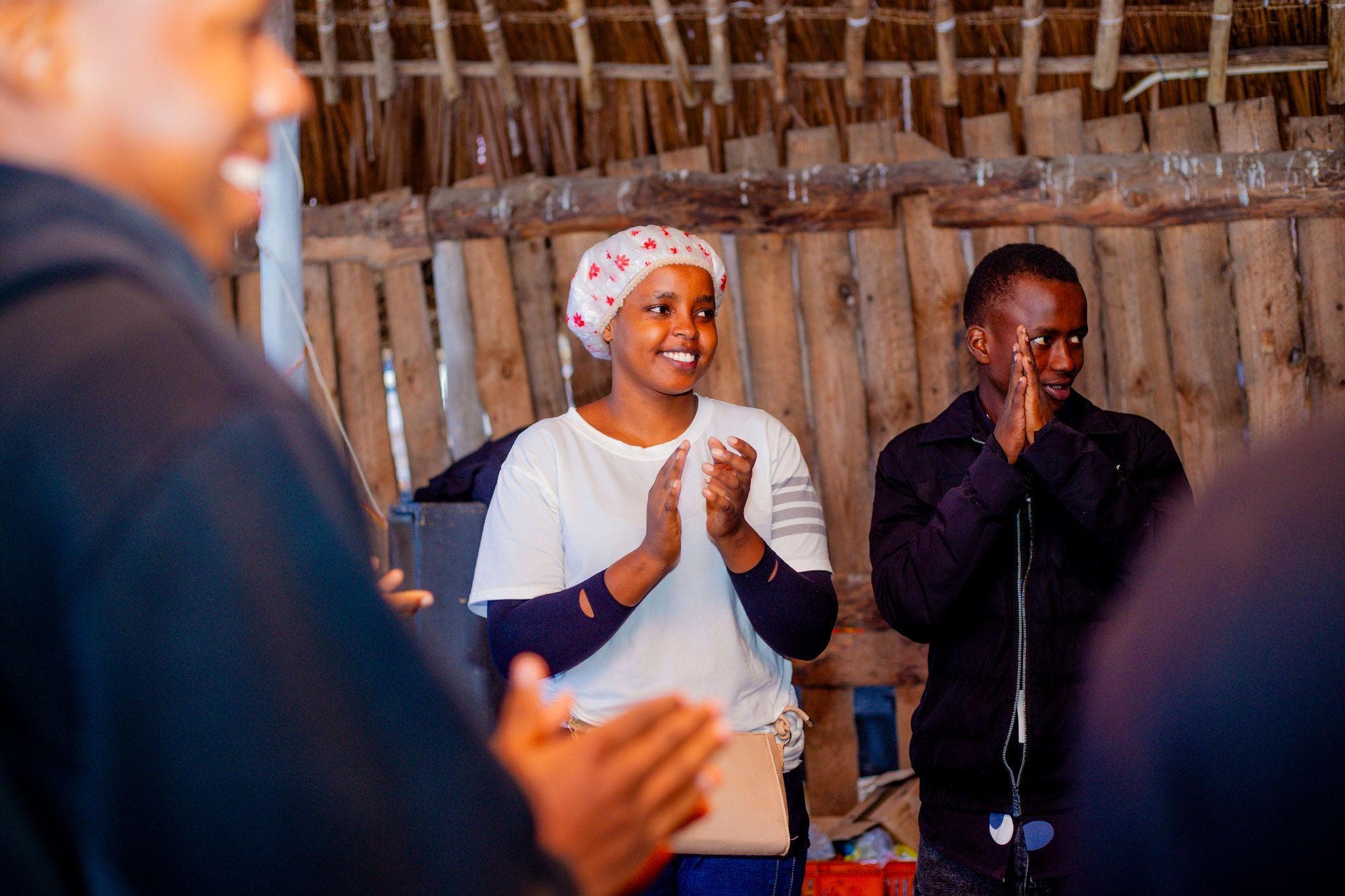 Participants smiling and applauding in the covered meeting space.